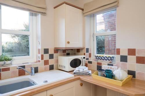 a kitchen with a sink and a microwave at Rose Cottage, Snettisham, Norfolk in Snettisham