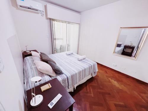 Schlafzimmer mit einem Bett mit einem Tisch und einem Spiegel in der Unterkunft Departamento Peatonal Sarmiento in Mendoza