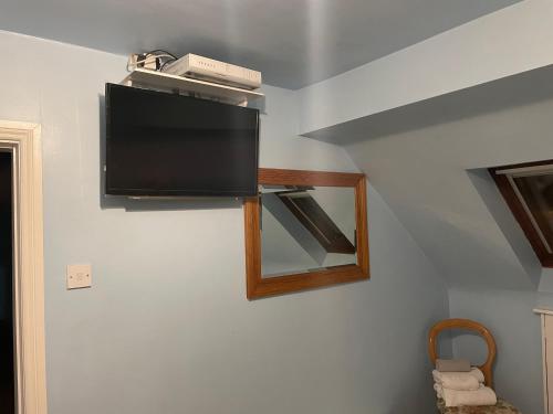 TV de pantalla plana colgada en la pared en Kinsale B&B en Scilly