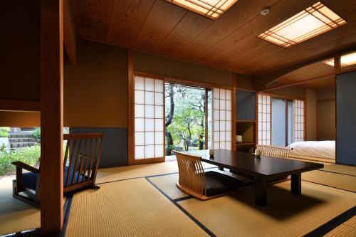 伊豆市にある修善寺 離れ宿　鬼の栖のテーブルとベッドが備わる客室で、窓があります。