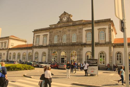 personas caminando frente a un edificio con una torre de reloj en HOSPEDARIA LONDRES, en Oporto