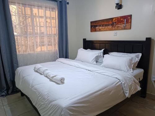a large bed with white sheets and pillows at Stylish 2 bedroom apartment in Nairobi