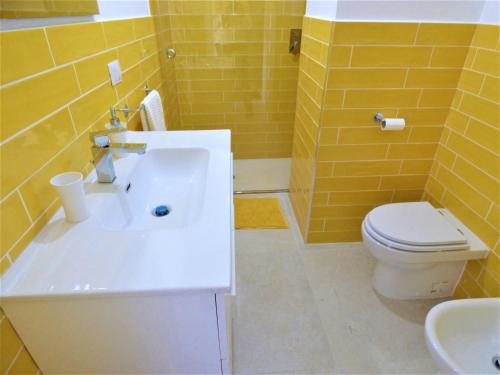 a yellow bathroom with a toilet and a sink at Napoletando b&b in Naples