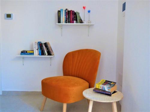 einen orangenen Stuhl und einen Beistelltisch mit Büchern in der Unterkunft Napoletando b&b in Neapel