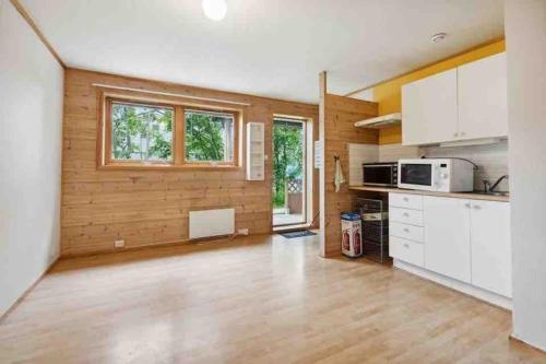 a kitchen with white cabinets and a wooden wall at 36 sqm Studio aparatment B in Tromsø