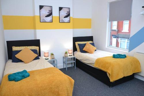 a bedroom with two beds with yellow and blue sheets at Cozy home near city, sleeps 5, Free Parking, WIFI in Liverpool