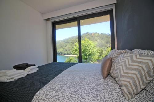 a bedroom with a bed with a large window at Apartamento Lobo - Casas Barca do Rio - Geres in Geres