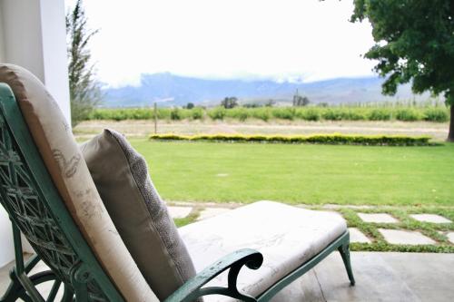 a green chair sitting on a porch with a view of a field at De Hoop Farm - mountain view in Breerivier