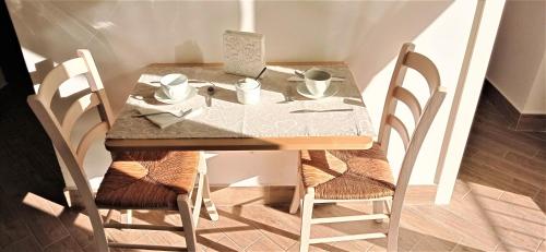 a small table with two chairs and a table with cups at Napoletando b&b in Naples