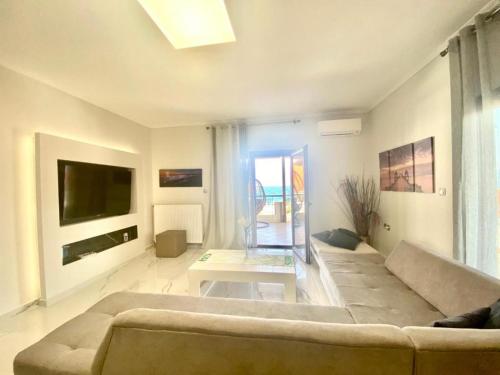 uma sala de estar com um sofá e uma televisão em Villa Amalia Sun Beach em Nea Vrasna