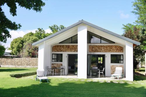 a house with glass doors and chairs on the grass at De Hoop Farm - Mountain View in Breërivier