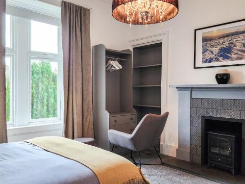 a bedroom with a bed and a fireplace and a chandelier at Riverside Cottage in Larkhall