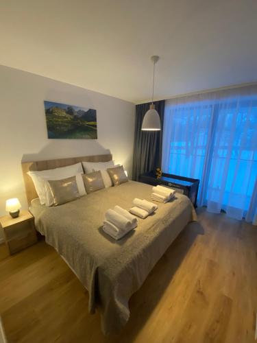 1 dormitorio con 1 cama grande y toallas. en Apartmán Betula-apartmán v srdci Vysokých Tatier, en Vysoké Tatry