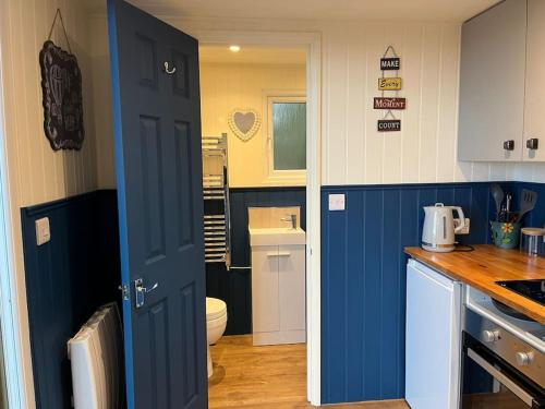 a kitchen with a blue door leading to a bathroom at Ramblers retreat in Shrewsbury