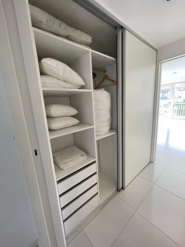 Armario con estanterías y almohadas blancas en Moderno departamento de 52 mts en el centro en Comodoro Rivadavia