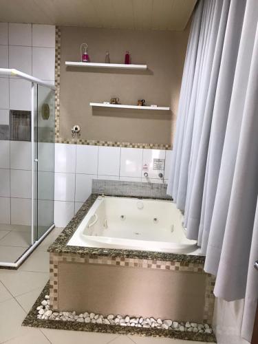 a bath tub in a bathroom with a shower at Pousada Reserva Penedo in Penedo