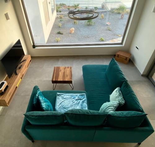 a green couch in a living room with a large window at Evgoro - Infinite View in Tsoútsouros
