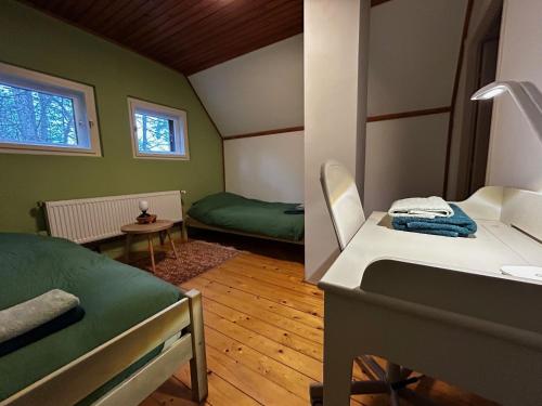 Cette petite chambre comprend deux lits et une table. dans l'établissement Forest-side home by recreational lake, à Kunfehértó