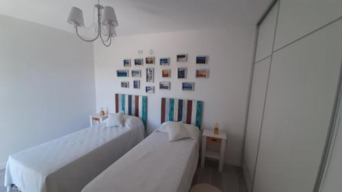 2 camas en una habitación blanca con cuadros en la pared en Monte Hermoso Premium en Monte Hermoso