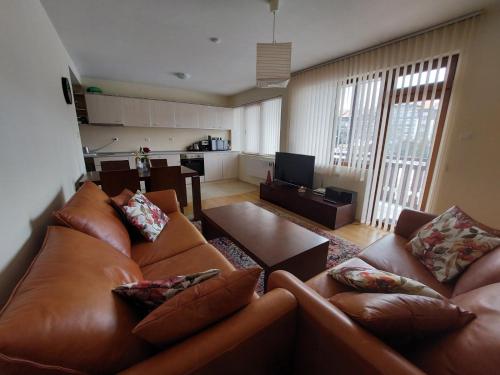 sala de estar con sofá de cuero marrón y mesa en Apartment Pirin, en Bansko