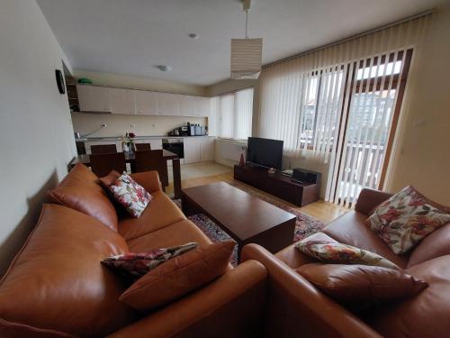 a living room with a brown leather couch and a table at Apartment Pirin in Bansko