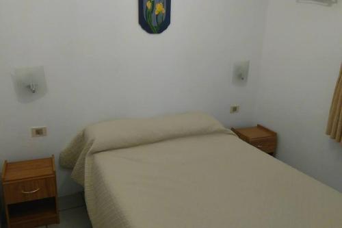 1 dormitorio con cama blanca y reloj en la pared en La Rosadita, un escape tranquilo en La Pedrera., en La Pedrera