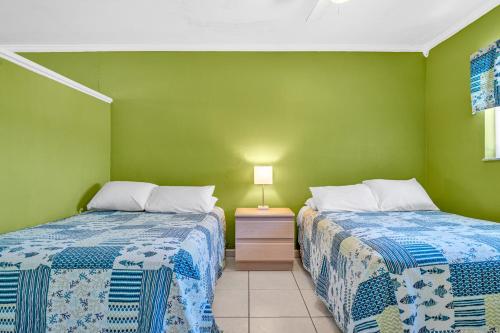 two beds in a room with green walls at Old Wooden Bridge Resort & Marina in Big Pine Key