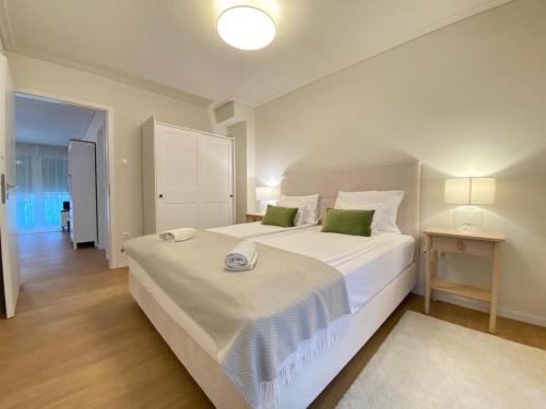 1 dormitorio con 1 cama blanca grande con almohadas verdes en Cosy inner city getaway bestern, en Szeged