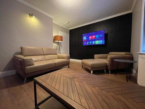 a living room with couches and a flat screen tv at Windsor House in Falkirk