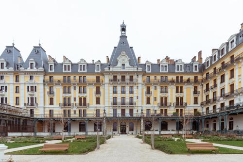 un gran edificio con bancos delante en Ancien Palace Bernascon vue sur lac Classé 3 étoiles, en Aix-les-Bains