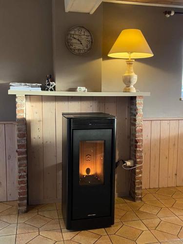a fireplace with a lamp and a clock on the wall at Ô Macra House - Aubel, Pays de Herve in Aubel
