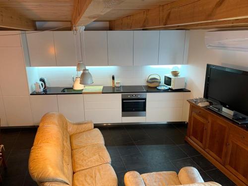 a living room with a couch and a tv in a kitchen at CASA DO ESTÁBULO - Vila Garcia - Trancoso in Carigas