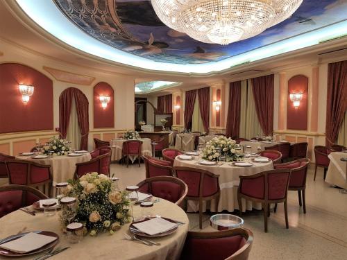 una sala da pranzo con tavoli, sedie e lampadario a braccio di Parco dei Principi Hotel a Roccella Ionica