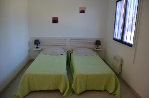 2 Betten in einem kleinen Zimmer mit 2 Fenstern in der Unterkunft Villa Fior 50 in Santa-Maria-Poggio