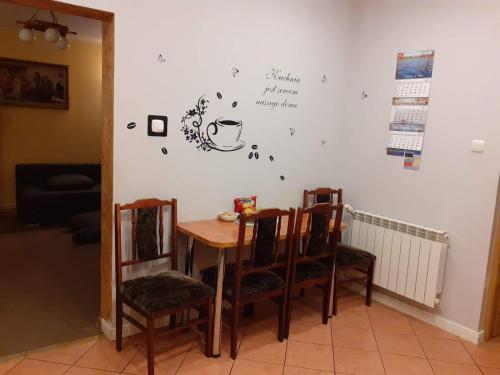una mesa y sillas en una habitación con una pared en Jak w Domu en Lubaczów