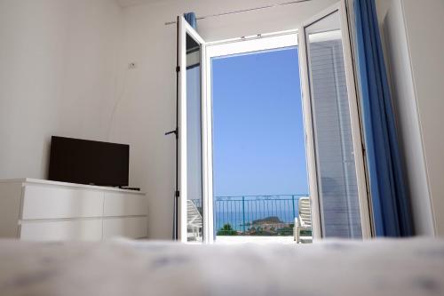 a bedroom with a sliding glass door with a television at Sole Mare - Casa Vacanze Chiavarello in Licata