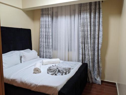 a bedroom with a bed with white sheets and a window at Bliss haven gardens two bedroom apartment in Nairobi