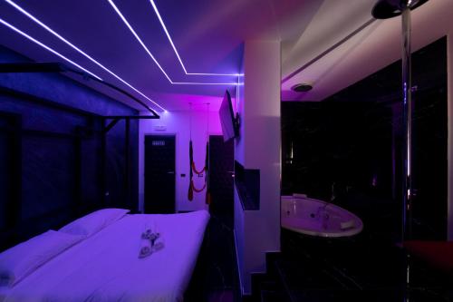 Zimmer mit einem Bett, einer Badewanne und lila Beleuchtung in der Unterkunft Suite Luxury BDSM in Rom