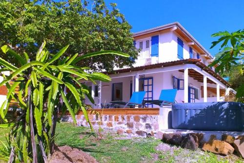 a house with blue chairs in front of it at Villa Campêche Marine in Le Marin