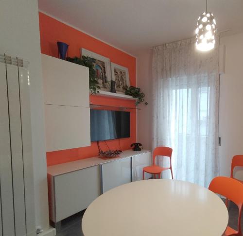 a dining room with a white table and orange walls at Tre Continenti - Appartamento con parcheggio privato in Ronchi dei Legionari