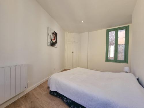 a white bedroom with a bed and a window at Mon Petit Patio - 4 chambres in Fourques