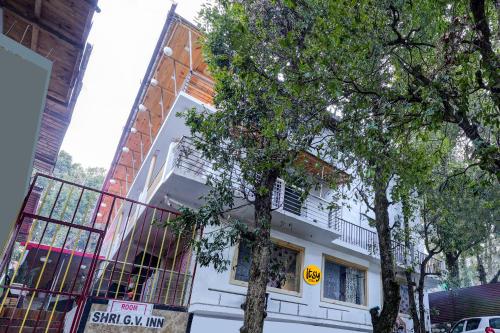 a white building with trees in front of it at Itsy By Treebo - Shri Gv Inn 600 Mtrs From Tiffin Top in Nainital