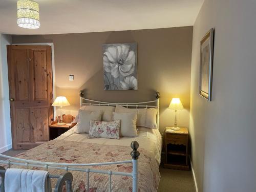 a bedroom with a bed and two night stands with lamps at Gingerbread Cottage in Chideock