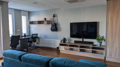 salon z niebieską kanapą i telewizorem z płaskim ekranem w obiekcie Luxurious villa-apartment with spacious terrace w Pradze