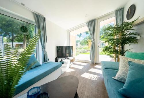 a living room with blue couches and a large window at Chalet Panorama near Efteling - with garden and swimmingpool Europarcs in Kaatsheuvel