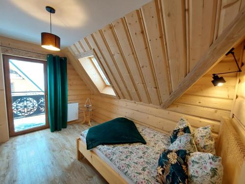 a bedroom with a bed in a room with wooden walls at DOMEK Z BALA ELITA in Kościelisko