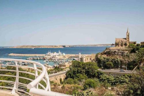 a view of a city with a harbor and the water at New, Modern Ground Floor Apartment with Pool in Għajnsielem