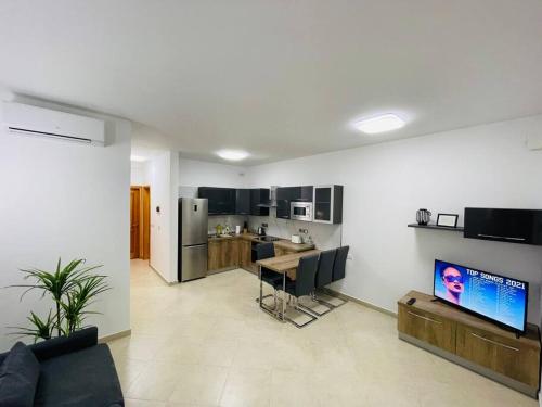 een woonkamer met een bank en een tafel en een keuken bij New, Modern Ground Floor Apartment with Pool in Għajnsielem