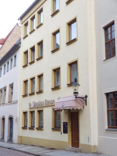 een groot wit gebouw met een luifel op een straat bij Pension Krone in Freiberg