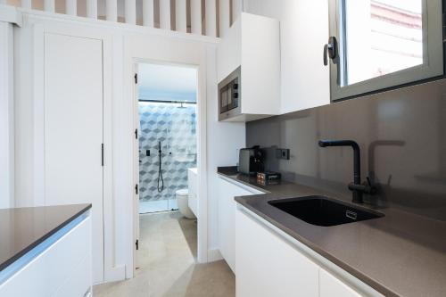 una cocina con armarios blancos y fregadero en apartamentos montevideo 6, en Sevilla